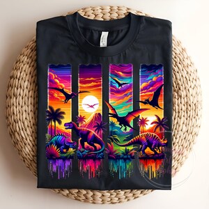 May include: Black t-shirt featuring a vibrant, colorful dinosaur design. The graphic includes various dinosaurs, palm trees, and a sunset scene with flying pterodactyls. The design is rendered in a vivid, rainbow-like palette.