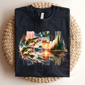 May include: A black t-shirt with a graphic print of two bass jumping out of the water. The graphic is a watercolor style with a sunset and trees in the background.