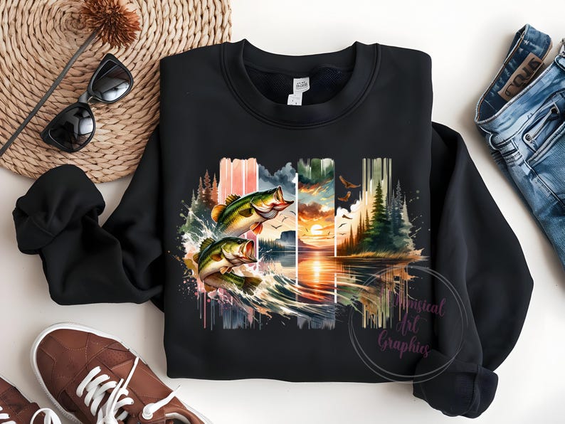 May include: Black sweatshirt with a watercolor design of two bass jumping out of the water. The design includes a sunset, trees, and a lake.