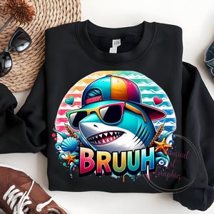 Puede incluir: Sudadera negra con un tibur&oacute;n de dibujos animados con gafas de sol y una gorra. El tibur&oacute;n est&aacute; sobre un fondo a rayas de colores con la palabra "BRUUH" en una fuente vibrante y goteante. El dise&ntilde;o incluye corazones, conchas marinas y estrellas de mar.