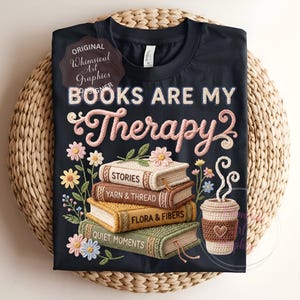 May include: Black t-shirt with the text "BOOKS ARE MY Therapy" in pink and white script. The design includes a stack of books, flowers, and a coffee cup. The books have titles like "STORIES" and "YARN & THREAD".