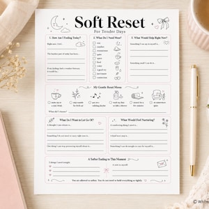May include: A white paper worksheet titled Soft Reset For Tender Days featuring sections for self-reflection, including prompts about feelings, needs, and a gentle reset menu with icons for tea, fresh air, music, washing, stretching, and quiet time.