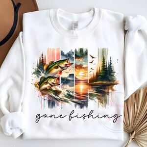 May include: White sweatshirt with a watercolor design of two bass jumping out of the water, a sunset, and trees. The text "gone fishing" is printed below the design.