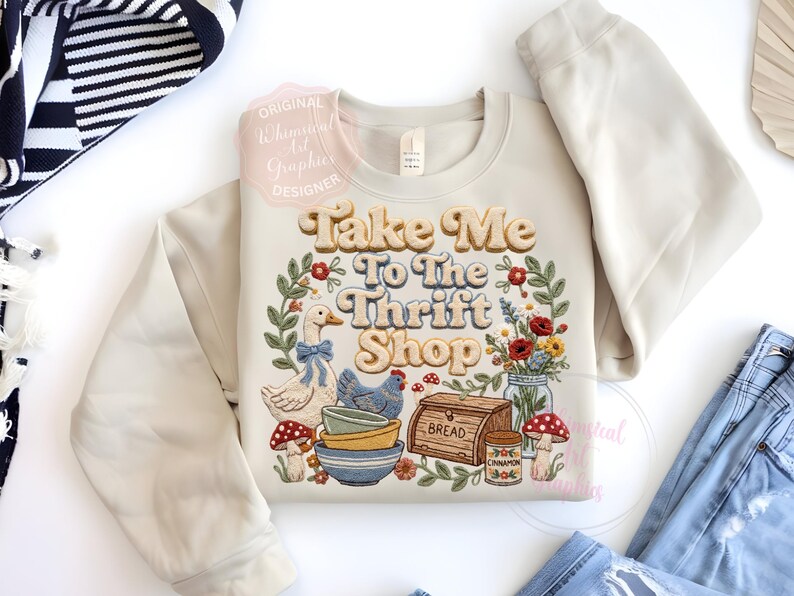 Puede incluir: Sudadera color crema con la frase "Take Me To The Thrift Shop" en una fuente retro, rodeada por una corona floral e ilustraciones de un ganso, una gallina, cuencos y setas. Un dise&ntilde;o de inspiraci&oacute;n vintage.