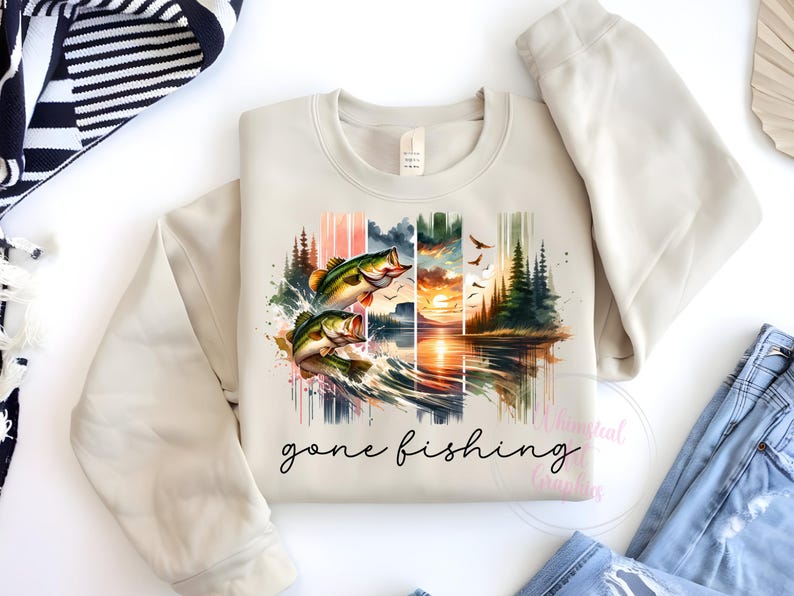 May include: A beige sweatshirt with a watercolor design of two bass jumping out of the water. The design includes a sunset, trees, and the text "gone fishing".