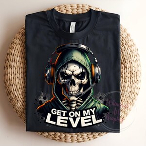 May include: Black t-shirt with a graphic of a skeleton wearing a green hooded sweatshirt and headphones. The text "Get on my level" is printed below the graphic.