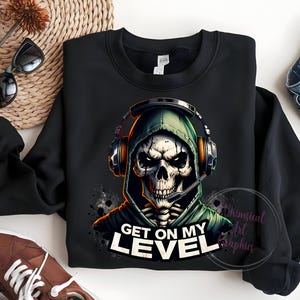 May include: Black sweatshirt with a graphic of a skeleton wearing a green hooded sweatshirt and headphones. The text "Get on my level" is printed below the graphic.