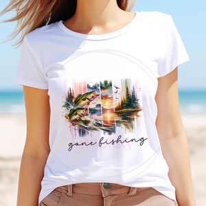 May include: White t-shirt with a watercolor design of a sunset over a lake with two fish jumping out of the water. The text "gone fishing" is written below the design.