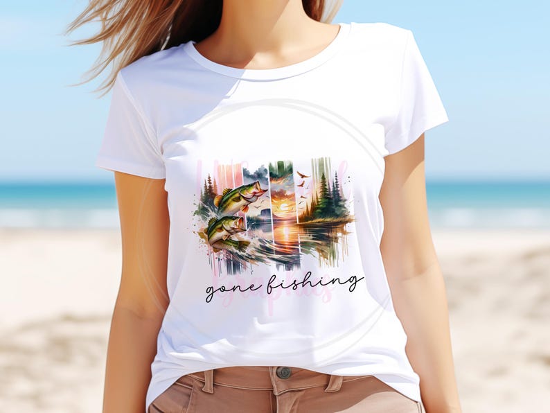 May include: White t-shirt with a watercolor design of a sunset over a lake with two fish jumping out of the water. The text "gone fishing" is written below the design.