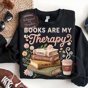 May include: Black sweatshirt with the text "BOOKS ARE MY Therapy" and a stack of books with floral embroidery. The books are labeled "STORIES", "YARN & THREAD", "FLORA & FIBERS", and "QUIET MOMENTS". A coffee cup is also featured.