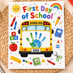 May include: A white rectangular sign featuring the text First Day of School and a yellow school bus illustration with a blue and green handprint in the center. The design includes a sun, rainbow, apple, crayons, glue, scissors, and the year 2026.