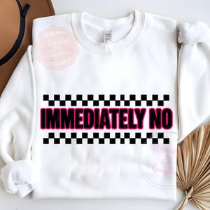 Puede incluir: Sudadera blanca de cuello redondo con el texto "IMMEDIATELY NO" en rosa y un dise&ntilde;o a cuadros blancos y negros. La parte superior de manga larga tiene cuello redondo. Un sombrero marr&oacute;n y una planta seca est&aacute;n en el fondo.