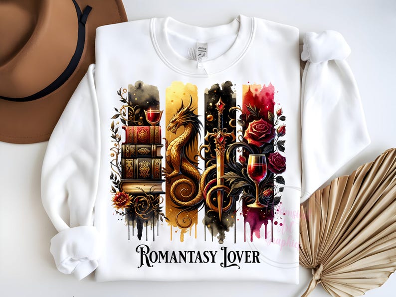 May include: White sweatshirt with a graphic design of a dragon, a sword, a glass of wine, and a stack of books. The graphic is surrounded by watercolor-like splatters of red, yellow, and blue. The text "Romantasy Lover" is printed below the graphic.