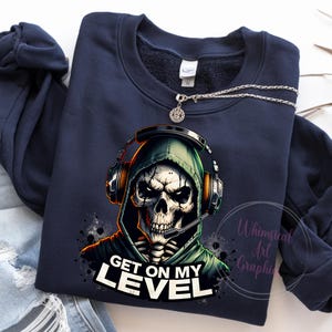 May include: A navy blue sweatshirt with a graphic of a skeleton wearing a hooded sweatshirt and headphones. The text "Get on my level" is printed below the graphic.