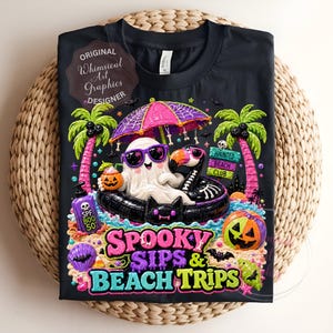 May include: Black t-shirt featuring a whimsical Halloween design. A ghost wearing sunglasses floats in a black inner tube under a pink umbrella. The shirt includes the text "Spooky Sips & Beach Trips" and a "Haunted Beach Club" sign.