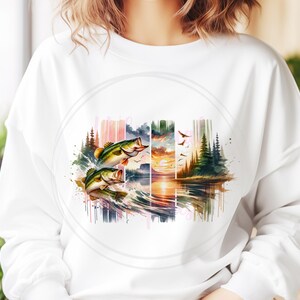 May include: A white sweatshirt with a watercolor design of two bass jumping out of the water. The design also includes a sunset, trees, and a lake.
