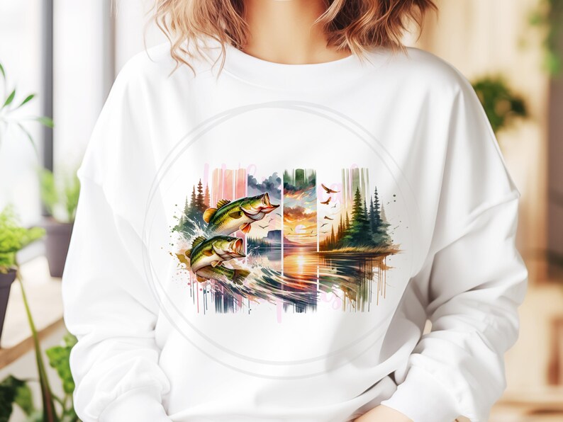 May include: A white sweatshirt with a watercolor design of two bass jumping out of the water. The design also includes a sunset, trees, and a lake.