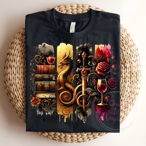 May include: A black t-shirt with a graphic design featuring a gold dragon, a sword, a stack of books, and wine glasses with red roses. The design is in a watercolor style with splashes of color.
