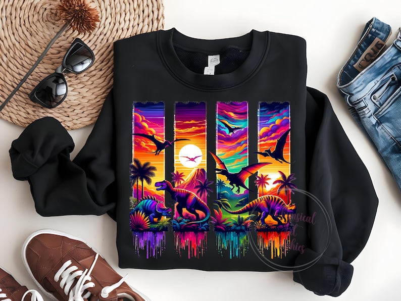 May include: Black sweatshirt featuring a vibrant, colorful graphic of dinosaurs and pterodactyls against a sunset backdrop. The design includes palm trees and a mountain silhouette, with a rainbow-colored, dripping effect at the bottom.