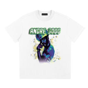 Op de afbeelding: Wit T-shirt met een afbeelding van Andre 3000 in een kleurrijke, artistieke stijl. De tekst "ANDRE 3000" staat in een groene en witte lettertype boven de afbeelding. Het shirt heeft een klassieke ronde hals en korte mouwen.