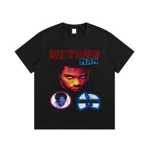 Puede incluir: Camiseta negra con un gráfico de Method Man y el texto "METHOD MAN" en rojo y azul. La camiseta también incluye dos gráficos circulares, uno con un retrato y el otro con un logotipo azul y blanco.