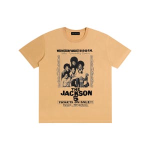 Puede incluir: Camiseta de color amarillo mostaza con un gráfico en blanco y negro de The Jackson 5. El gráfico incluye el texto "WEDNESDAY-AUGUST 18-8:00 P.M. Tulsa Assembly Center" y "TICKETS ON SALE!! Carson Attractions".