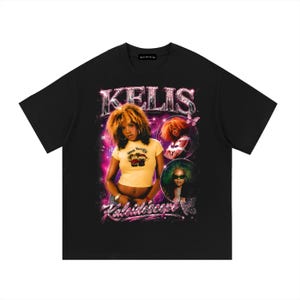 May include: A black short-sleeve t-shirt featuring a graphic print of the artist Kelis. The design includes the text KELIS and Kaleidoscope in a metallic font, surrounded by pink nebula effects, butterfly accents, and two circular photo insets.