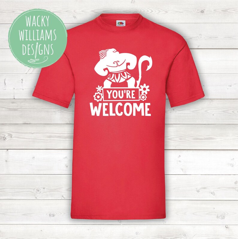 May include: Red t-shirt with a white graphic of a cartoon character from the movie Moana. The character is holding a spear and has a flower behind him. The text "You're Welcome" is printed below the character.