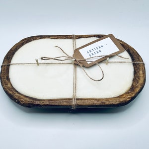 May include: A white candle in a wooden dough bowl with a brown paper tag that says "Artisan Bread". The candle is tied with twine.