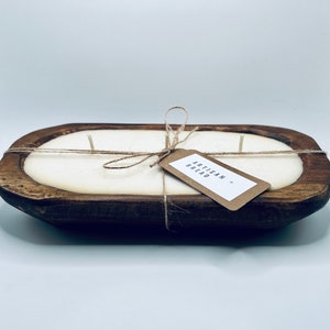May include: A white candle in a wooden bread bowl with a brown paper tag that says "Artisan Bread".