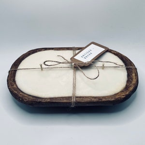 May include: A white candle in a wooden dough bowl with a brown paper tag that says "Artisan Bread". The candle is tied with twine.