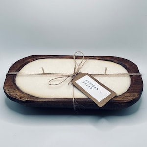 May include: A white candle in a wooden bread bowl with a brown paper tag that says "Artisan Bread".