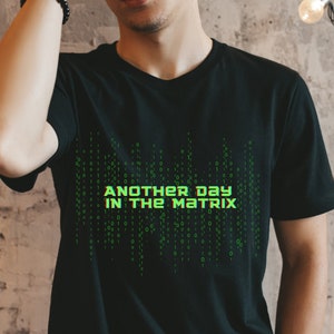 May include: A black t-shirt with a green graphic print of binary code and the text "Another Day In The Matrix".
