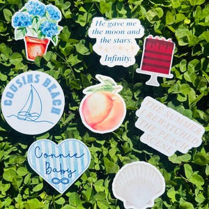 May include: A collection of stickers with various designs, including a sailboat, a peach, a seashell, a cake, and a pot of blue flowers. Some stickers have text: "Cousins Beach", "Connie Baby", "He gave me the moon and the stars. Infinity.", and "The Summer I Rewatched The Peach Scene."