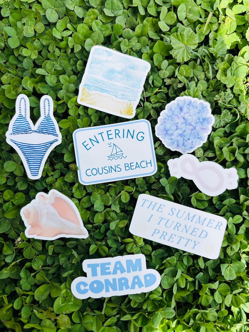 May include: A collection of stickers with a beach theme, including a blue and white striped bikini, a seashell, and a sign that says "Entering Cousins Beach." Other stickers include a beach scene, a hydrangea, and text that says "The Summer I Turned Pretty."