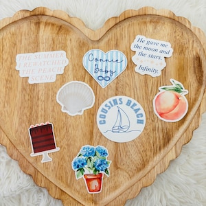 May include: A heart-shaped wooden tray with a scalloped edge holds several stickers. Stickers include text that reads "The Summer I Rewatched The Peach Scene", "Connie Baby", and "He gave me the moon and the stars. Infinity."
