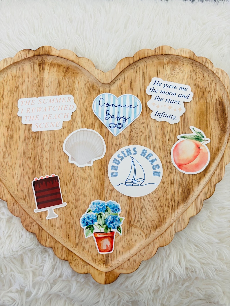 May include: A heart-shaped wooden tray with a scalloped edge holds several stickers. Stickers include text that reads "The Summer I Rewatched The Peach Scene", "Connie Baby", and "He gave me the moon and the stars. Infinity."