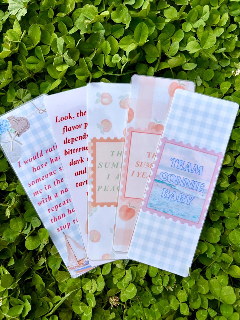 K&ouml;nnte beinhalten: F&uuml;nf dekorative Lesezeichen mit verschiedenen Designs und Texten. Ein Lesezeichen hat eine Segelboot-Illustration und Text. Ein anderes sagt "TEAM CONNIE BABY". Die anderen haben Pfirsich- und Blumenmuster.