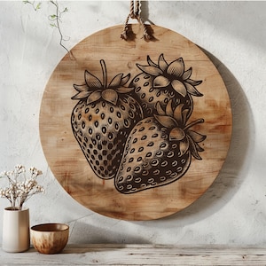 Puede incluir: Un letrero redondo de madera con un acabado rústico que presenta tres ilustraciones estilizadas en blanco y negro de fresas.