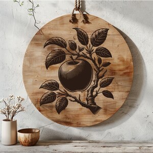 May include: A wooden round sign with a black and white illustration of an apple tree with a single apple on a branch. The sign is hanging from a rope.