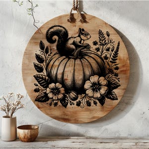 May include: A round wooden sign with a black and white illustration of a squirrel sitting on top of a pumpkin. The pumpkin is surrounded by flowers and leaves.