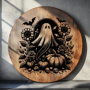 May include: Round wooden sign with a Halloween-themed design. The sign features a central ghost figure surrounded by pumpkins, sunflowers, roses, bats, and skulls. The artwork is in black against a light brown wood grain background.