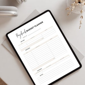 May include: A digital paycheck budget planner on a tablet. The planner has sections for income, expenses, summary, and notes. The text "Paycheck Budget Planner" is at the top in a handwritten font. The tablet is on a white surface.