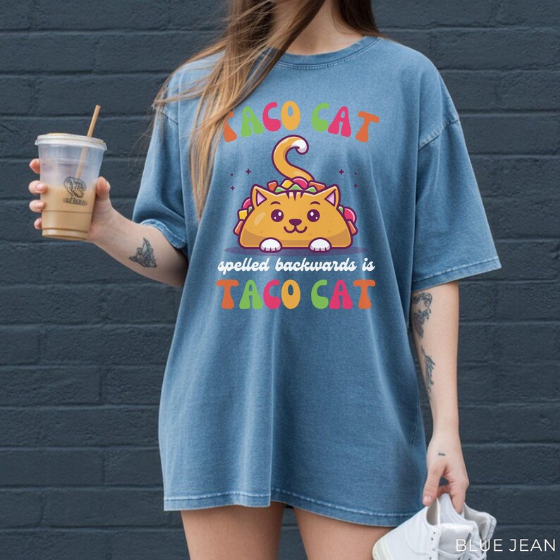 Funny taco cat graphic tee on Comfort Colors blue jean shirt featuring colorful “Taco Cat spelled backwards is Taco Cat” design with cute taco-shaped cat illustration.