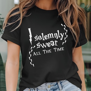 May include: Black t-shirt with white text that reads "I solemnly swear ALL THE TIME". The design includes a lightning bolt and a trail of footprints. The shirt is a classic crew neck.