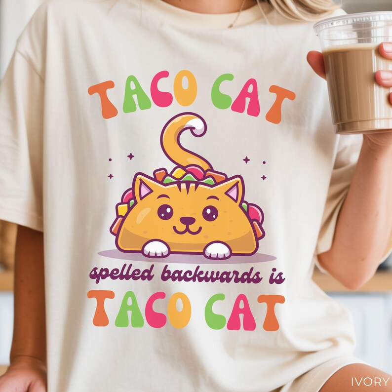 Cute taco cat graphic printed on ivory Comfort Colors unisex shirt with colorful retro-style lettering and kawaii taco cat illustration.