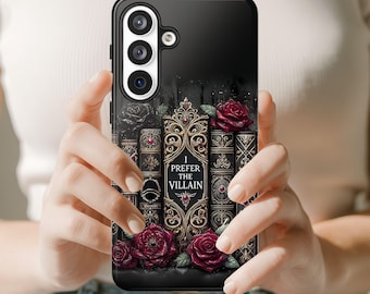 Könnte beinhalten: Eine schwarze Smartphone-Hülle mit einer Grafik antiker Bücher mit kunstvollen Goldverzierungen und dunkelroten Rosen. Der mittlere Buchrücken zeigt den Text I PREFER THE VILLAIN in weißer Schrift, umgeben von komplexen Filigranmustern.