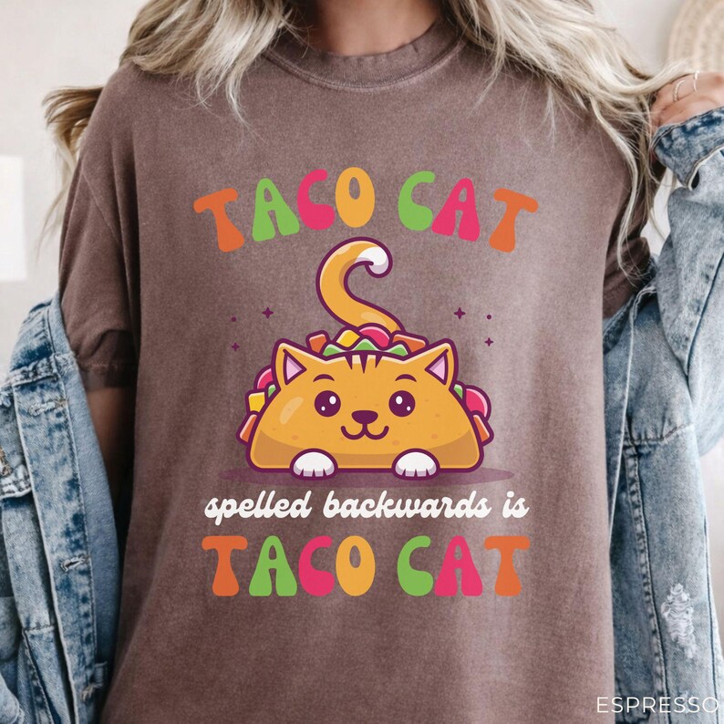 Funny taco cat shirt on espresso brown Comfort Colors garment-dyed tee featuring colorful cat taco illustration and playful palindrome phrase design.