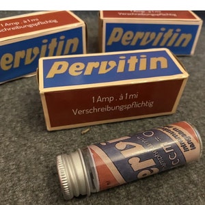 Puede incluir: Imagen de ampollas y cajas de Pervitin vintage. Las cajas son marrones y azules con letras doradas. La ampolla es cilíndrica con una tapa plateada y una etiqueta.