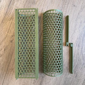 Puede incluir: Componentes verde oliva, con patrón de panal de abeja, impresos en 3D. El conjunto incluye un panel rectangular, una pieza cilíndrica curva y dos piezas rectangulares más pequeñas con elementos de enclavamiento.